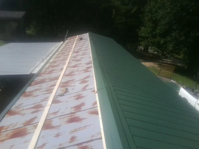Old rusted panels beside newly installed green metal roofing — Wind Damage Roof Repair by Roofing Brothers in Loves Park