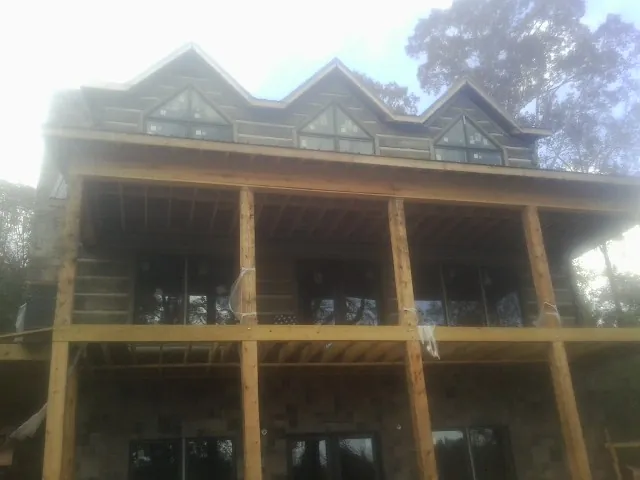 Dormers and porch framing on a large log home under construction — Roof Coating work by our crew in Loves Park