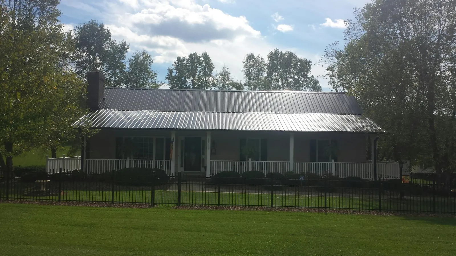 Gray metal roof on a brick ranch with a full width front porch — Gutter Guard Installation work by our crew in Loves Park