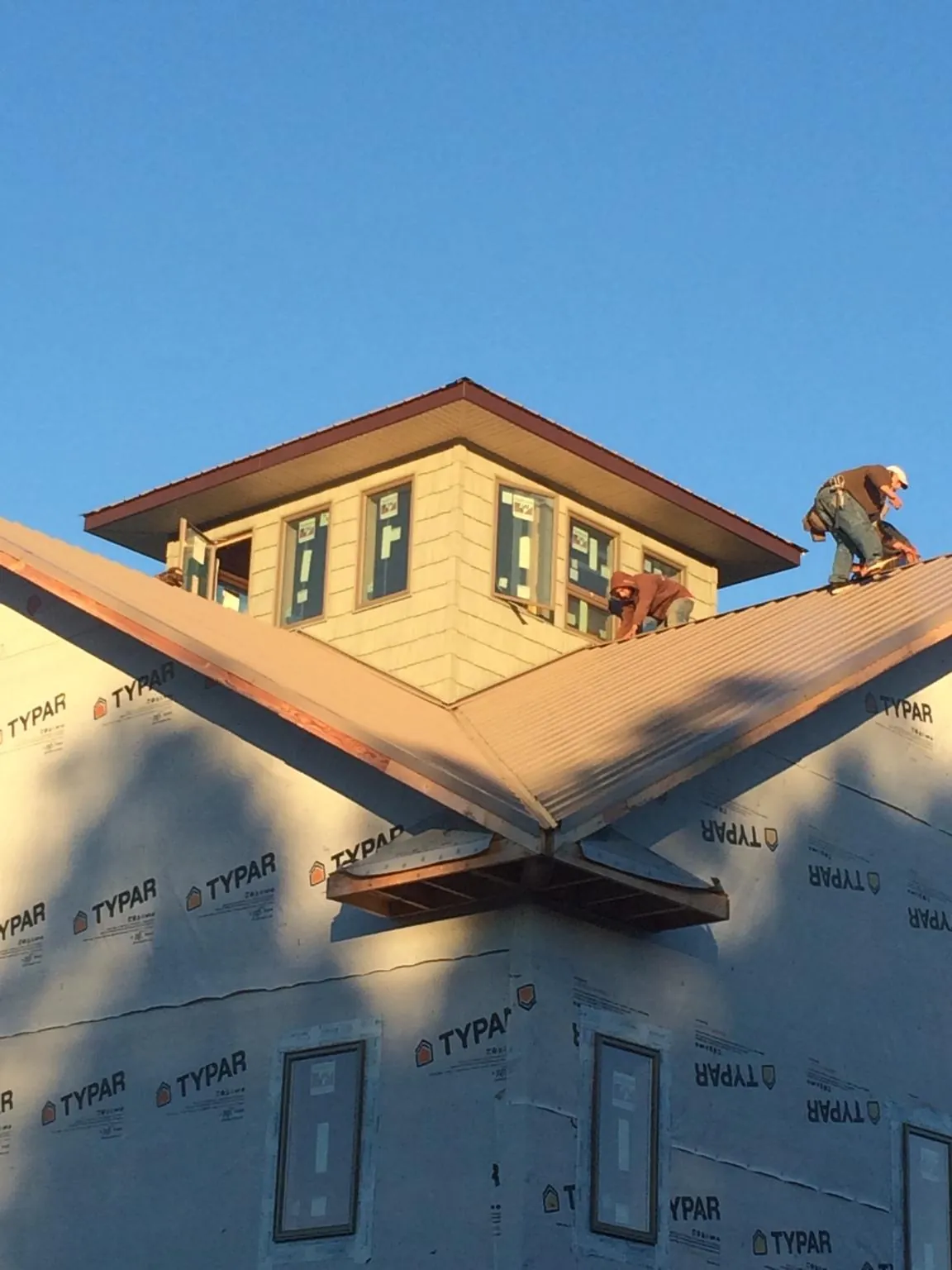 Roofers working around a rooftop cupola on a new metal roof at sunset — Roof Waterproofing in Loves Park by Roofing Brothers